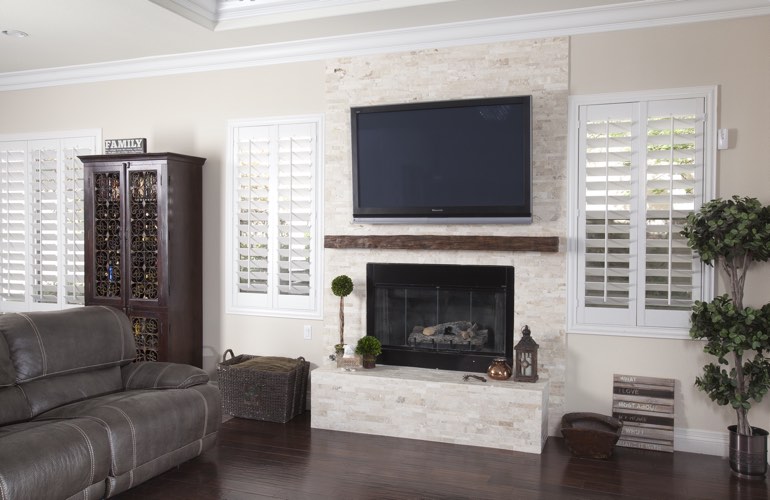 White plantation shutters in a San Diego living room with dark hardwood floors.
